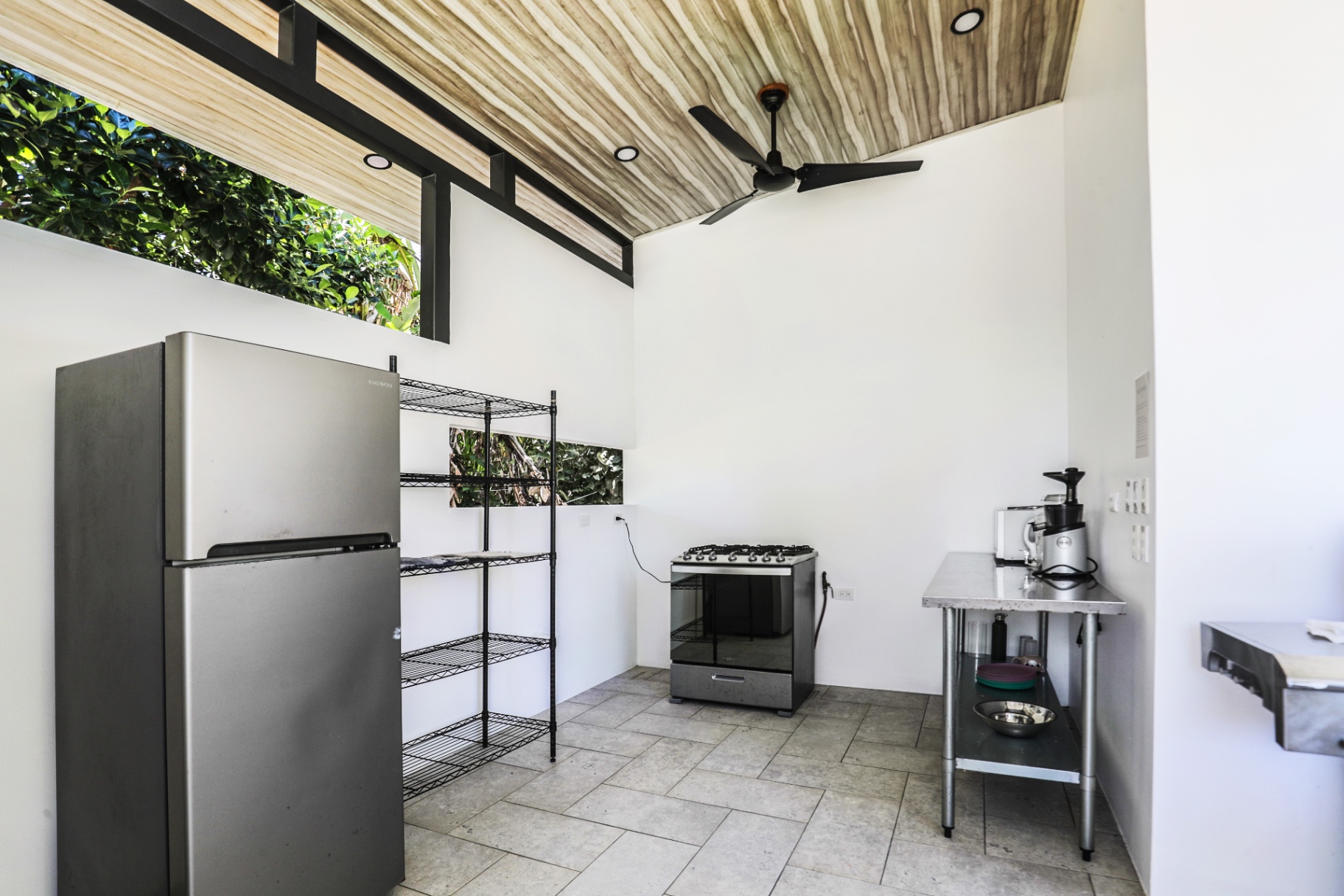 Shared outdoor kitchen with full-size fridge, gas range, prep table and cold-press juicer at The Retreat Uvita