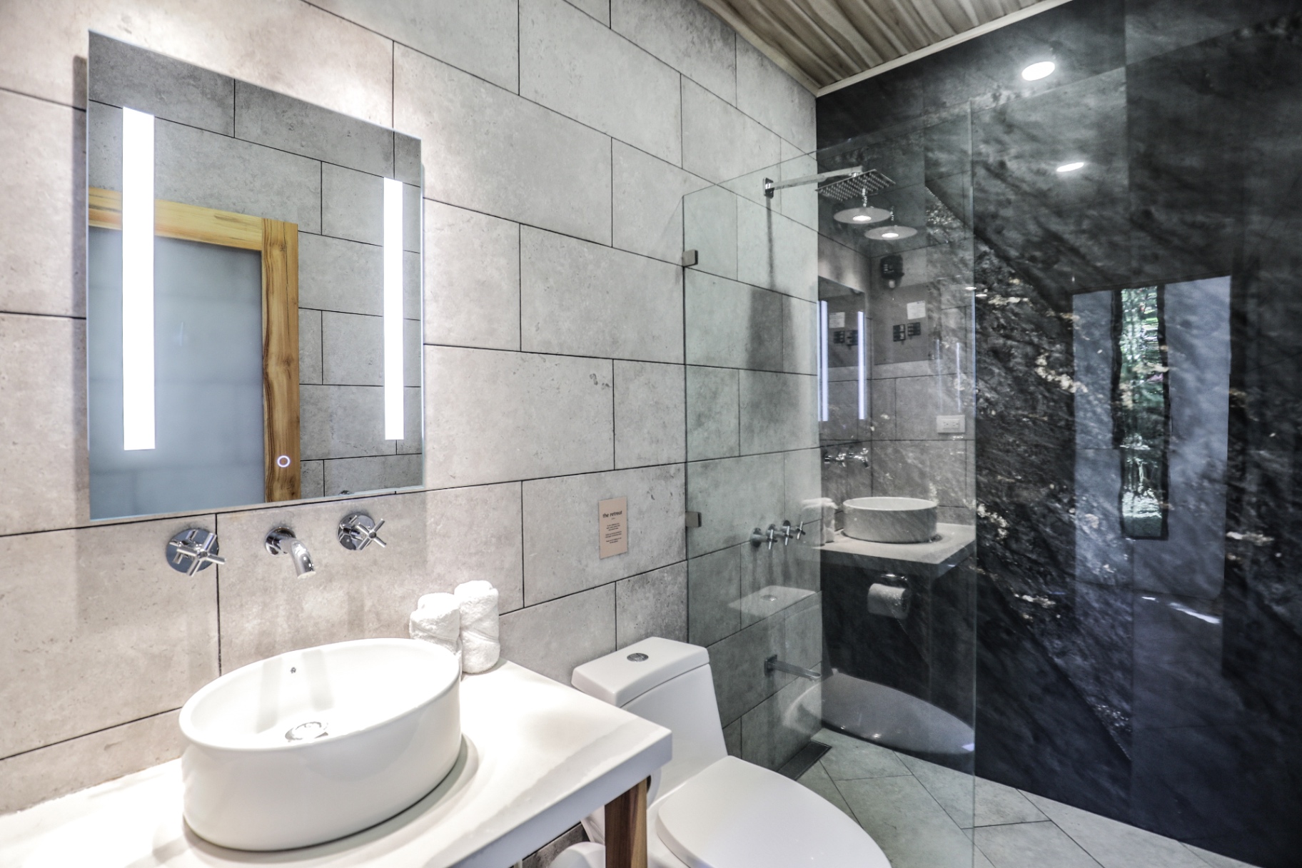 Concrete-tile bathroom with backlit LED mirror, vessel sink and black marble rain shower in Unit 1