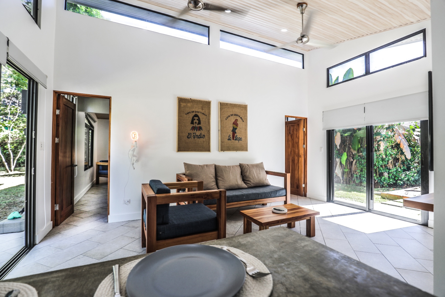 Bright living area with teak sofa, Costa Rican coffee-sack art and sliding doors to the garden in Unit 1