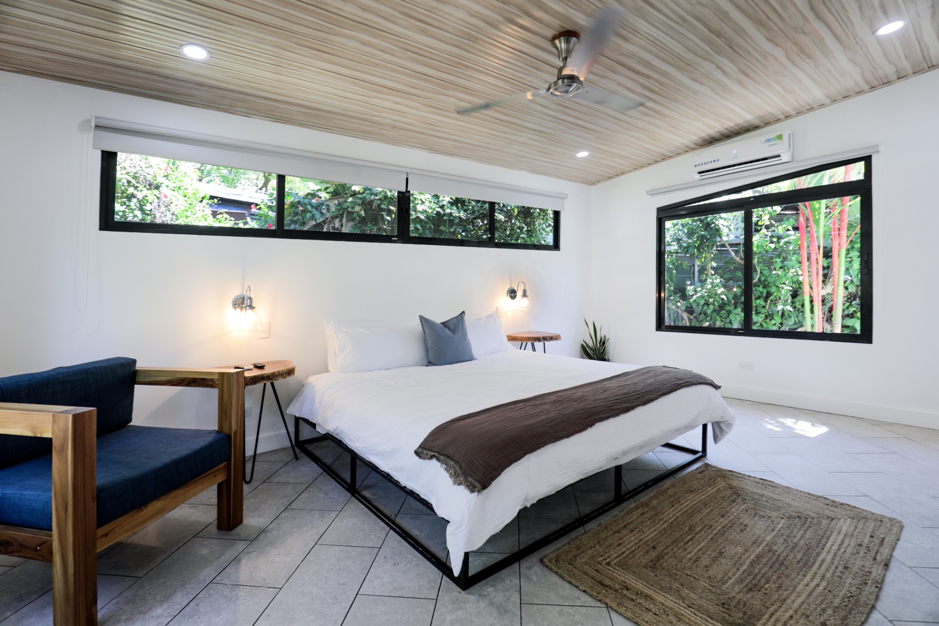 King bedroom with blue reading chair, wood ceiling and bright garden windows in Unit 1 at The Retreat Uvita