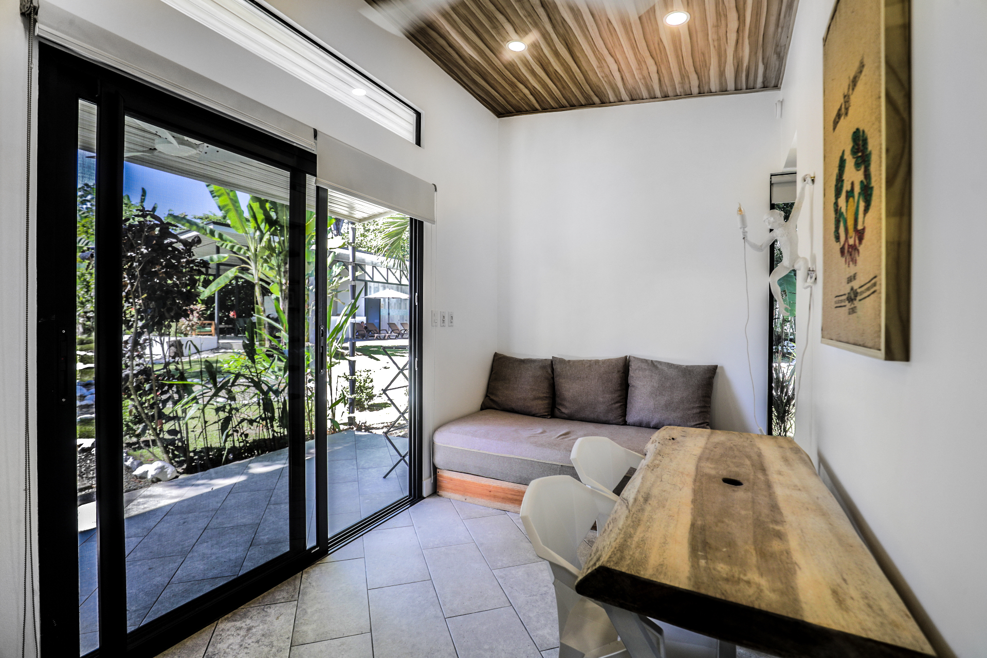 Lounge area with daybed sofa, live-edge table and sliding doors opening to the tropical garden in Unit 2
