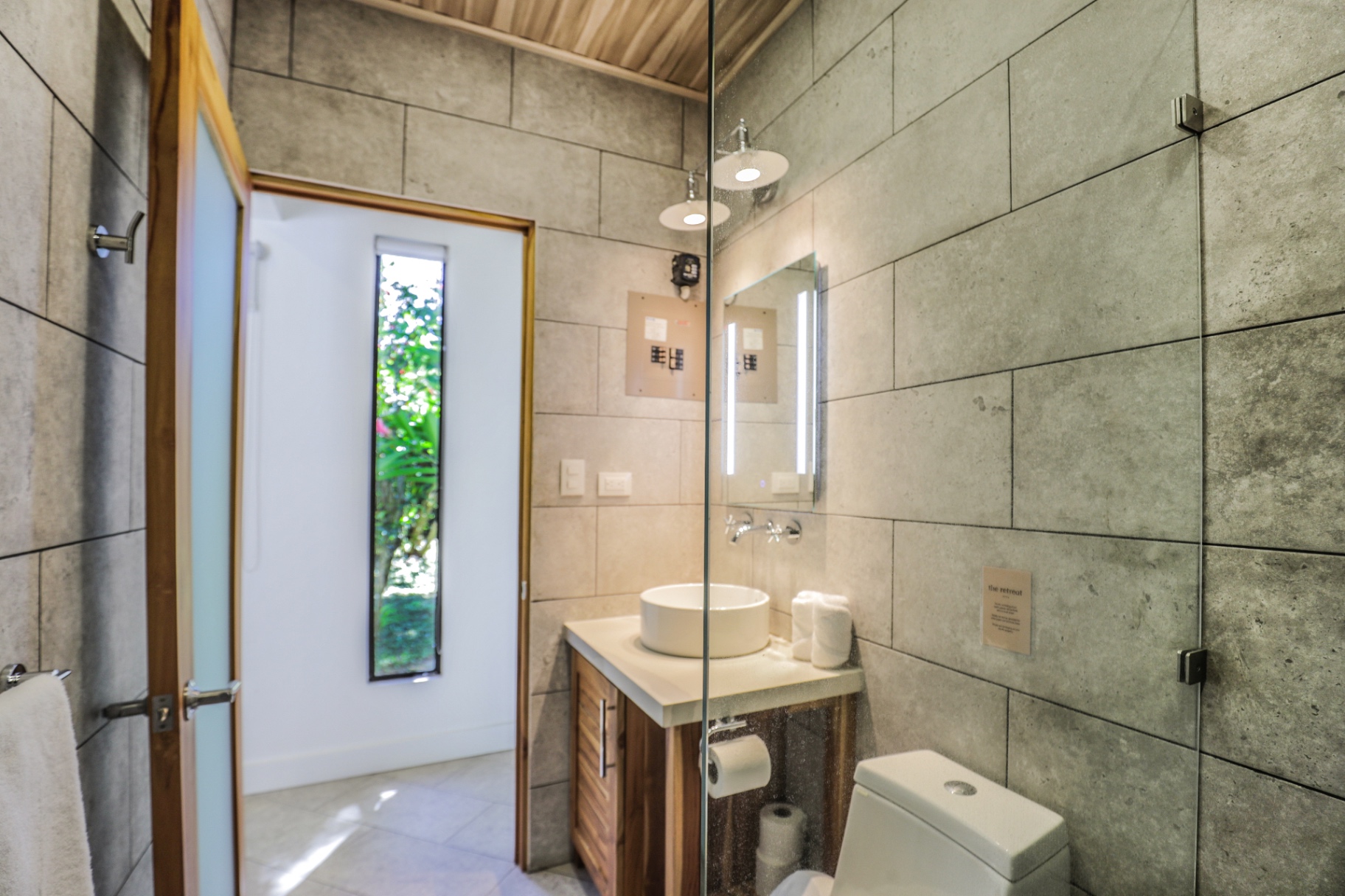 Concrete-tiled bathroom with glass shower, wood vanity and vessel sink in Unit 2 at The Retreat Uvita