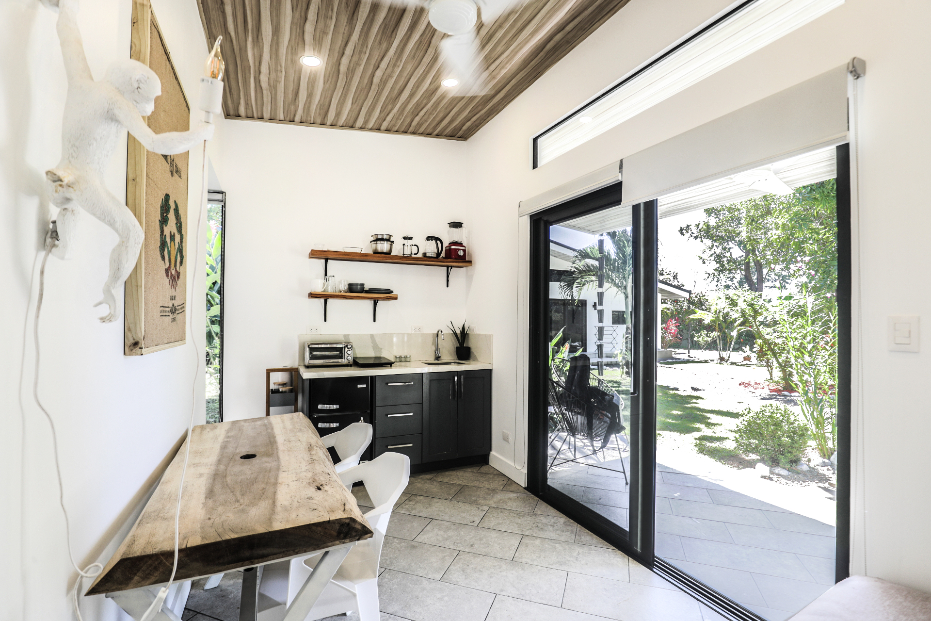 Kitchenette with cooktop, toaster oven, open teak shelving and live-edge dining table in Unit 2 at The Retreat Uvita
