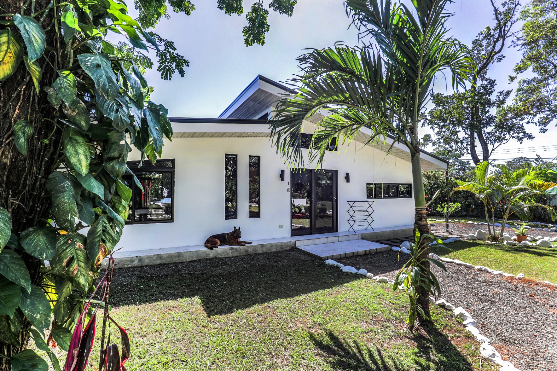 Exterior of a white boutique casita with tropical landscaping at The Retreat Uvita