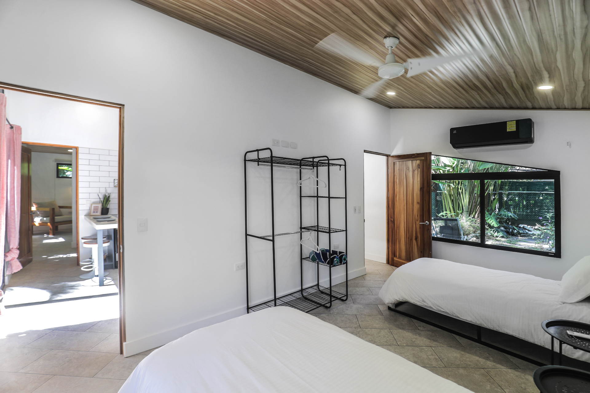 Twin bedroom view with two beds, hanging rack and doorway connecting back toward the kitchen in Unit 4